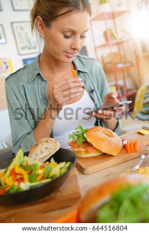 Trendy girl in restaurant taking picture of colourful dish with smartphone