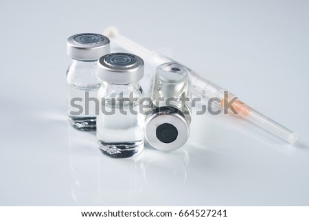 Medical ampoules, infusion and syringe with injection isolated on white background with copy space. Ampules with antibiotics closed with caps in a row. Syringe with needle  lying on the vial with drug Royalty-Free Stock Photo #664527241