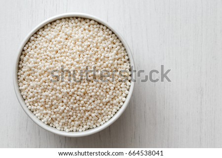 Dry tapioca pearls
 in white ceramic bowl isolated on painted white wood from above.