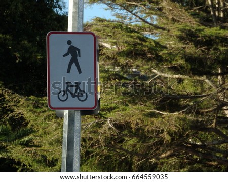 Cycle and pedestrian road metal sign on a white pole against green foliage
