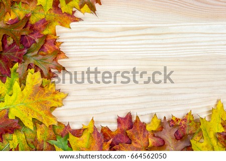 Various colored leaves lie on a wood background with copy space