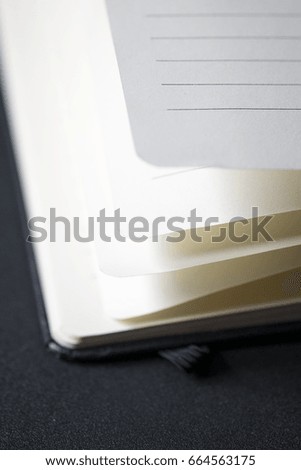 Opened business notepad with white sheets on the black desk