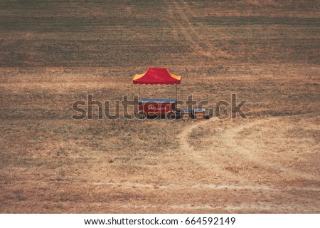 Retro pop corn stand, red and yellow, standing in the middle of nowhere in the big field, abandoned 