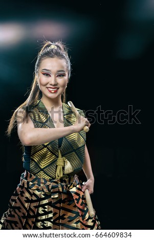 beautiful asian drummer girl with drumsticks, studio shot on a dark background. copy space.