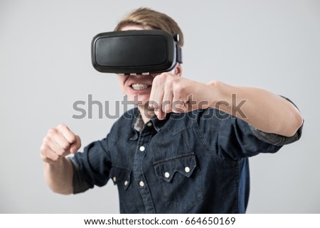 Man using virtual reality goggles on grey background