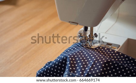female hand using sewing machine stitching fabic in studio