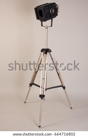 Old theater lamp on a tripod on a gray background.