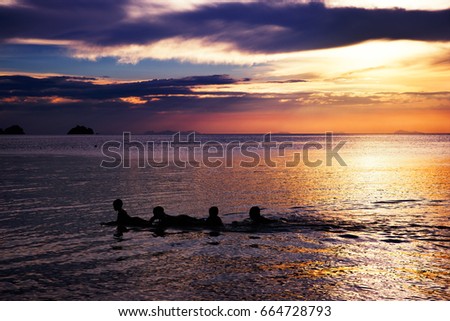 Playing and swimming kids in sea over beautifil sunrise in Thai