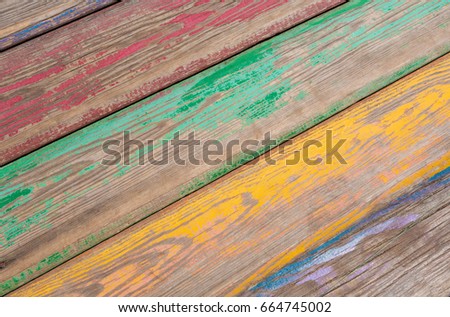 Detail of an old retro bench. The tree is painted with paint. Color pink, yellow, red, blue, black, green. Boards in the frame with a slope