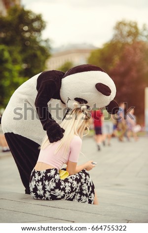 A man in a panda suit comforts an injured woman sitting on the steps in the city