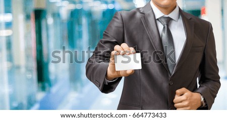 Businessman shows a payment card on blurred background.