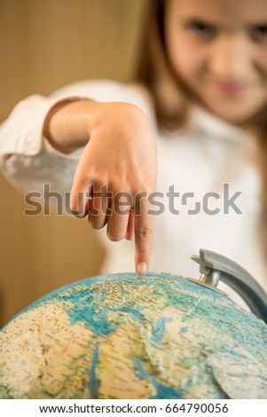 Little girl holding index finger on Earth globe
