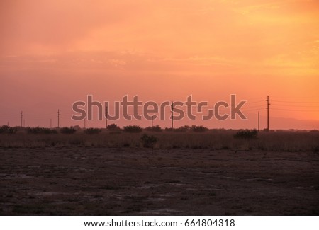 Pink and yellow cloudy evening skyline with dark power lines/Silhouettes of Power Poles with Sky Background in Violet Pink Orange and Yellow Colors/Power poles with orange yellow pink cloudy sky