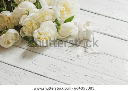 Bouquet of white peonies and present box on the wooden table, top view