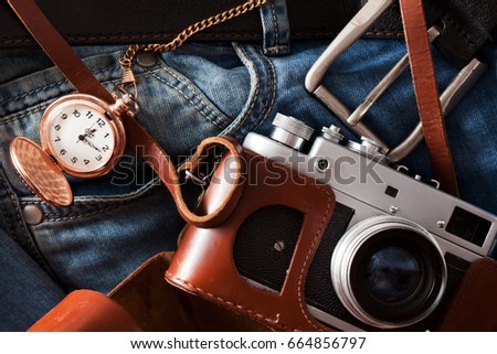 Old retro camera and pocket watch lies on a jeans