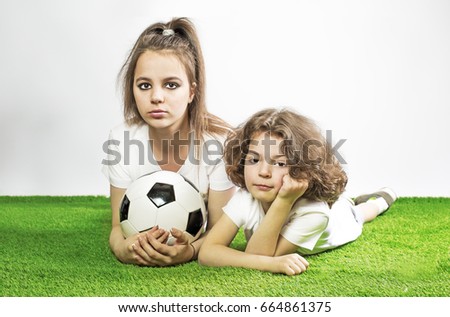 Cute kids in a sports T-shirt with a ball on a gray background. Sad beautiful children crying over her national football team's loss in soccer championship. 