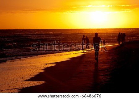 sunset silhouette of family playing in the beach