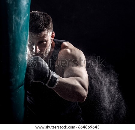 Studio shot of male boxer punching a boxing bag.	