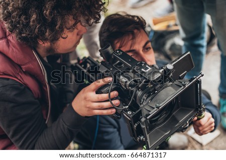 Behind the scene. Cameraman and assistant shooting the film scene with camera on outdoor location