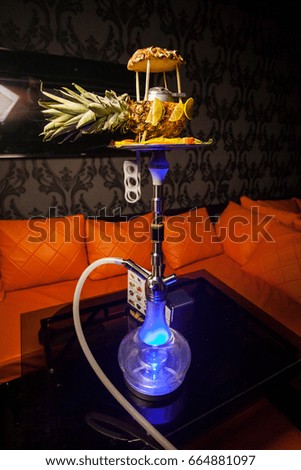 Hookah on the table in a bar / nightclub. Large hookah for Smoking tobacco made of metal, glass in a restaurant, black interior. Hookah on the table. hookah closeup photo