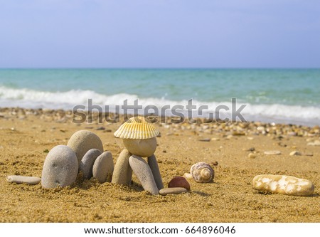 Funny figurine of woman lying on sea beach, made of pebbles and shells.