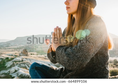 Young beautiful girl practicing yoga at the top of a mountain in Cappadocia at sunrise. Practices of relaxation.
