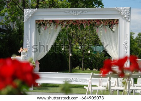 Wedding frame arch with flower composition and lace in green garden