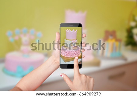 Little girl taking photo of her birthday cake with smartphone