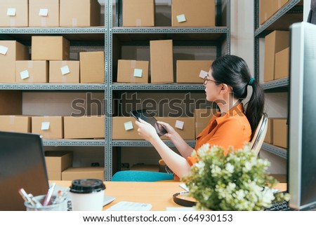 side view photo of pretty young online shopping company worker holding mobile digital tablet pad checking warehouse stock and looking at box confirm goods with vintage retro film color.