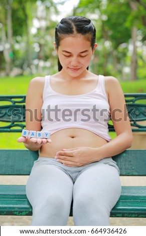 Woman holding character cubic "BABY" at her belly.