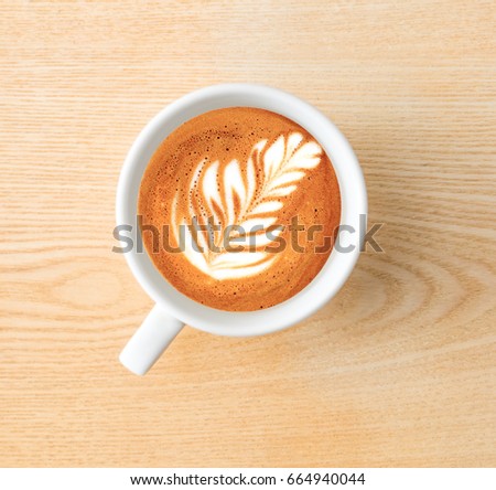 Above capture of white coffee cup with tree shape latte art on wood table at cafe