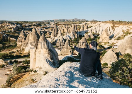 A traveler sits on top of the mountains and shows his hand at a beautiful view in Cappadocia in Turkey. Journey. Hiking.