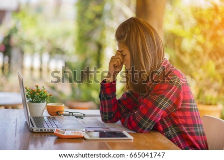 Feeling tired and stressed young woman of working age is working on a wooden table in the garden with evening sunlight