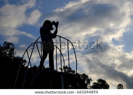 Girl photographer with camera to Explore mountain sunrise, in Silhouette.