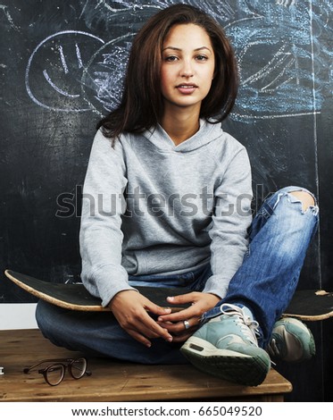 young cute teenage girl in classroom at blackboard seating on ta