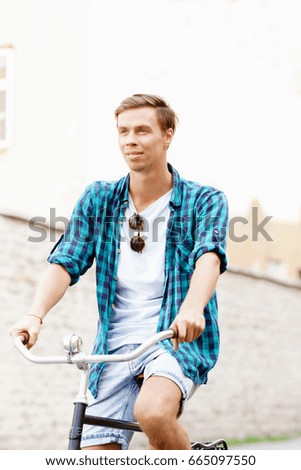 Handsome hipster riding a bicycle in old town. Traveling, holiday, vacation concept.