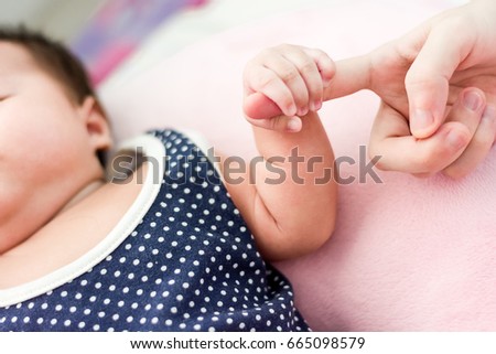 Baby hand gently holding mother finger againt blurred background