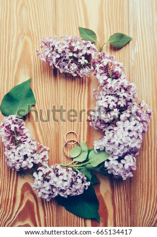 Gold wedding rings and lilac on a wooden background