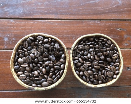 Roasted coffee beans in two ceramic cups,top view,on wooden table