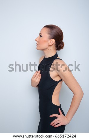 young, slender girl in a simple black dress. collected hair and professional makeup. posing in a photo Studio. clear skin