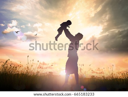 Father's Day concept: Silhouette father throwing son into sky on meadow autumn sunset background