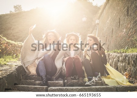 Three young girls sitting on the stairs at the public park. Three best friend making self picture in the public park. Girls sitting on stairs.