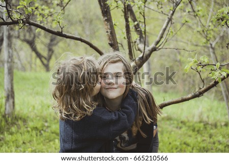 Sisters hugging and kissing in their grandparents backyard garden.