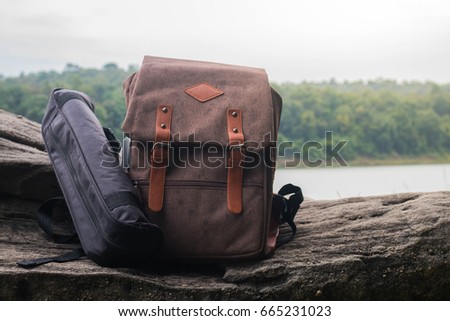 Travel backpack on the rock with landscape view of mountain and river.