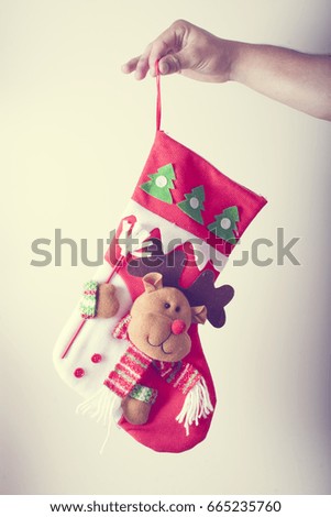 hand holds red christmas sock with traditional sweet treat