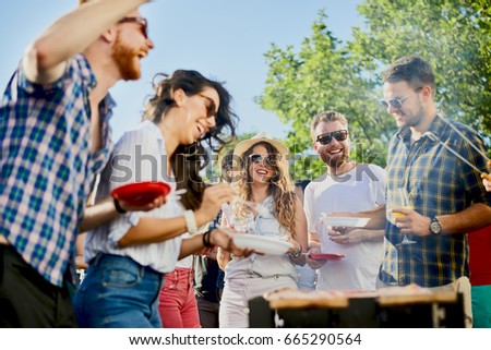 Group of friends eating, drinking, dancing and having a good time at outdoor party