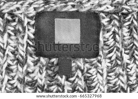 Blank clothes label on black and white wool knitted background