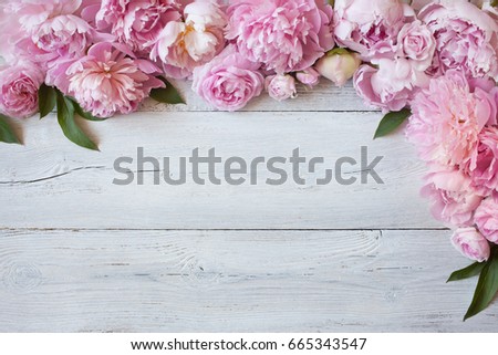 Pink peonies and roses on a white wooden background, copy space, greeting card.