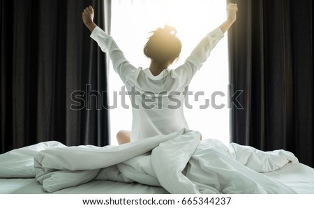 Asian women wake up from sleep. are  stretch herself  in the morning on the weekend sit on the bed at luxury room in Relax and weekend concept Royalty-Free Stock Photo #665344237
