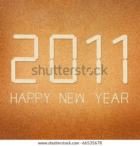 New Years card 2011, wood ice-cream stick isolated on cork board background